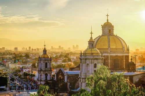 Basilica of Guadalupe with Mexico city skyline at sunset, Mexico - Ultimate Mexico Travel Guide