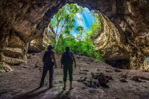 Two male explorers standing at bottom of circular cave opening in jungle of Chiapas, Mexico - Ultimate Mexico Travel Guide