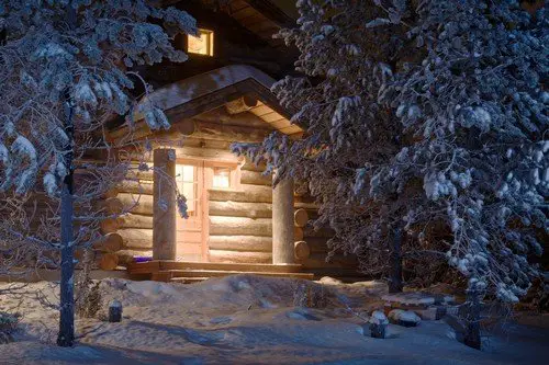 Cozy wooden cottage in dark winter forest - ultimate finland travel guide