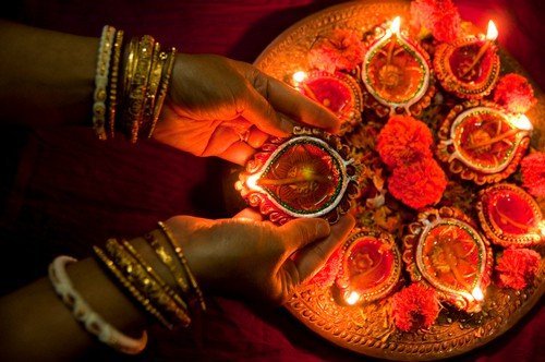 Hands holding Diwali lamps. Diversity, bokeh. - India Travel Guide