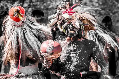 Indigenous men perform a traditional ceremony using feathers and black body paint to symbolize a jaguar