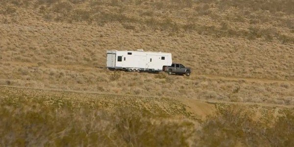 white travel trailer and truck on a mountain road