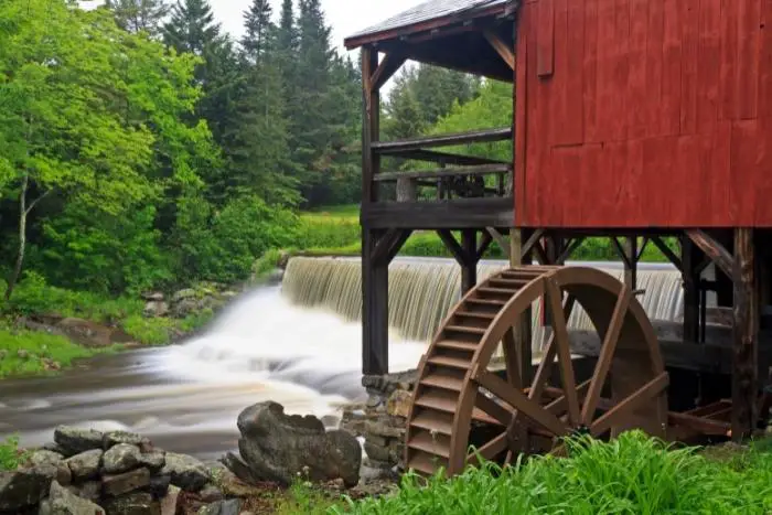 Water pours over a dem next to an old red mill in Weston, Vermont - Vermont Boondocking Spots